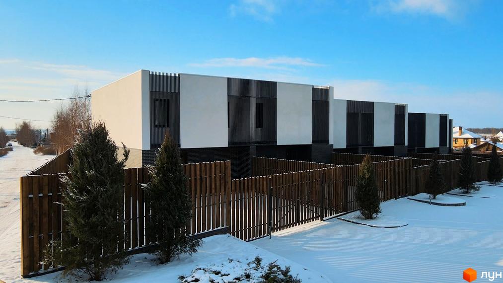Таунхаус Новоолександрівський – це сучасні будинки з білими фасадами та темними елементами, розташовані на засніженій ділянці з дерев'яним парканом.