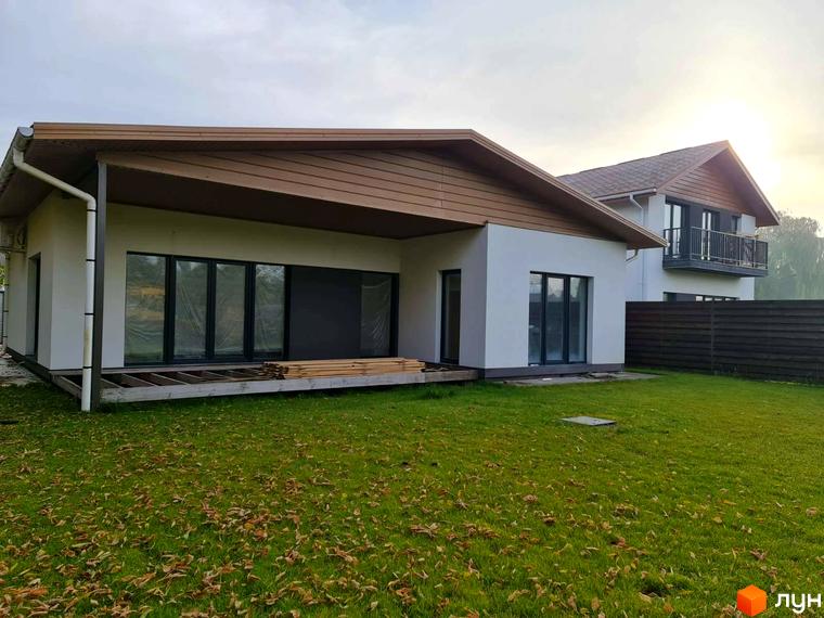 Котеджне містечко КМ Заміський: одноповерховий будинок з великими вікнами та терасою, зелена галявина з опалим листям.