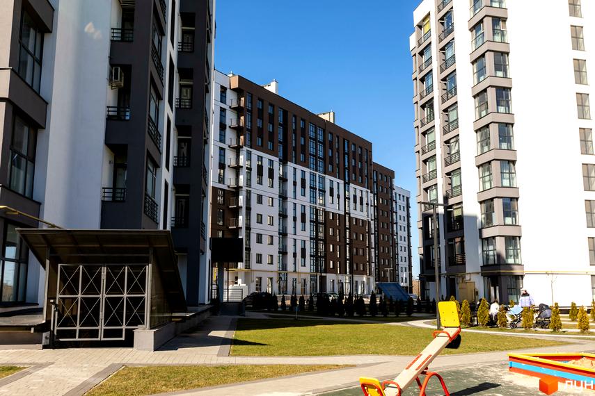 Житловий комплекс Супернова. Зовнішній вигляд будівель з коричневими та білими фасадами. Прибудинкова територія з дитячим майданчиком та зеленими насадженнями.