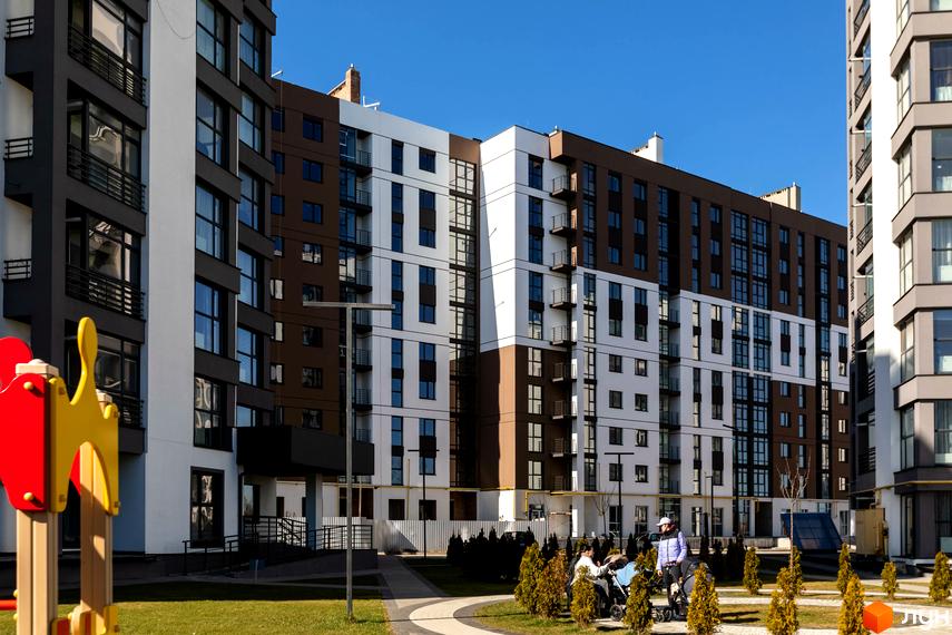 Житловий комплекс Супернова. Сучасна архітектура з білими та коричневими фасадами, великими вікнами та балконами. Прибудинкова територія з дитячим майданчиком та зеленими насадженнями.