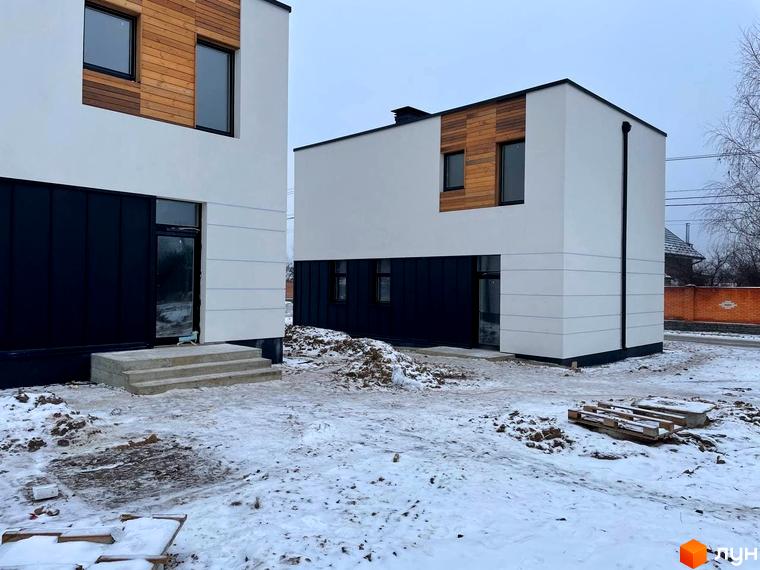 Зображення двох будинків в Котеджному містечку 10 Families. Двоповерхові будівлі з білими стінами та дерев'яними вставками.