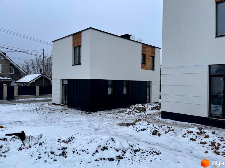 Котеджне містечко КМ 10 Families: двоповерхові будинки з білими фасадами та чорною нижньою частиною, дерев'яними вставками. Навколо засніжена територія з ділянками землі.