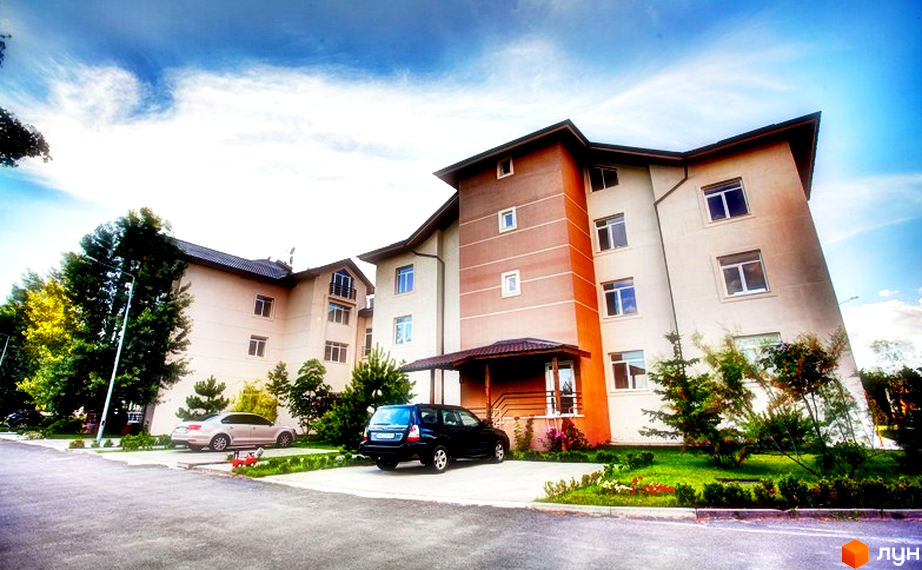 Житловий комплекс Бірюза з фасадом у світлих тонах та прибудинковою територією з зеленими насадженнями і парковкою.