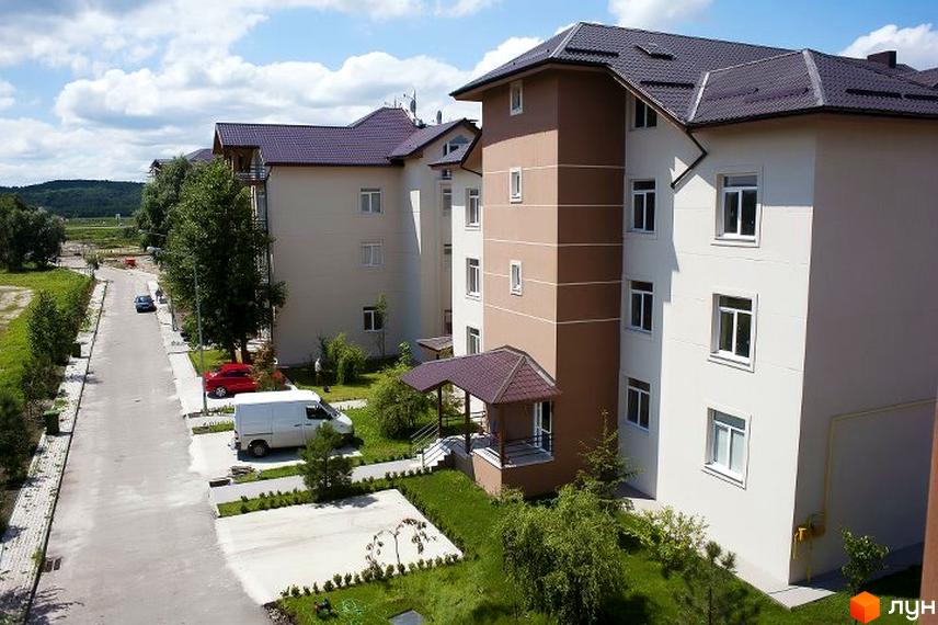 Житловий комплекс Бірюза з фасадом будинків та прибудинковою територією, озелененням і паркувальними місцями.