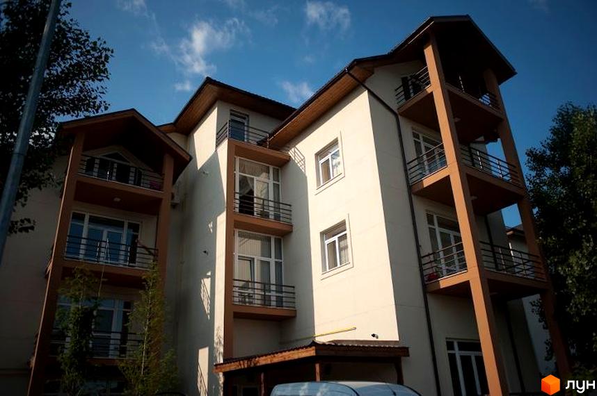 Житловий комплекс Бірюза - багатоповерхова будівля з балконами та вікнами під блакитним небом. Зовнішній вигляд будинку з коричневими елементами та білими стінами.