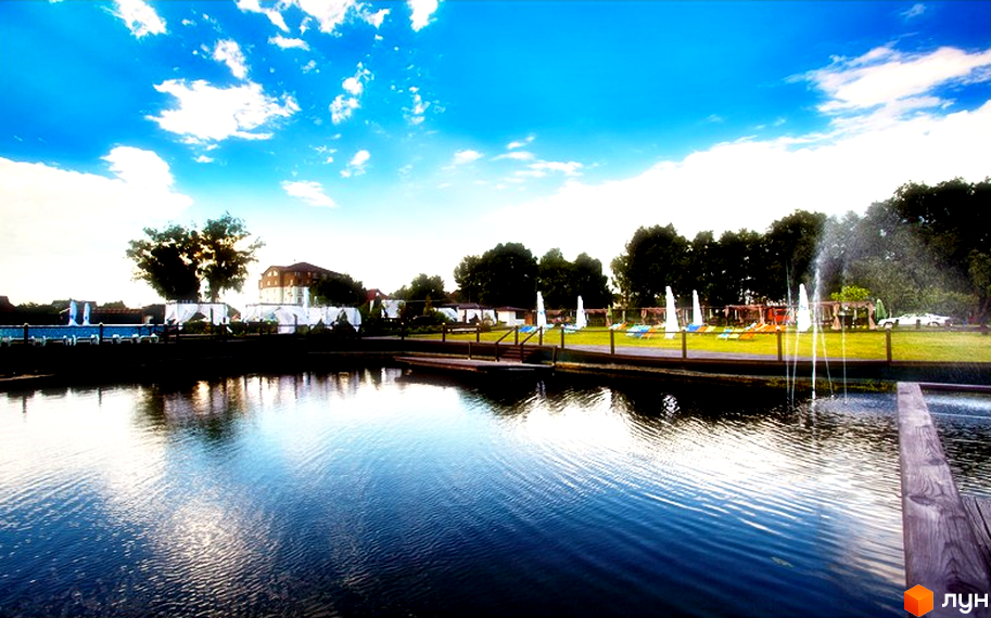 Житловий комплекс Бірюза: відпочинкова зона біля води з шезлонгами та парасольками. На території комплексу є фонтани та зелена зона.