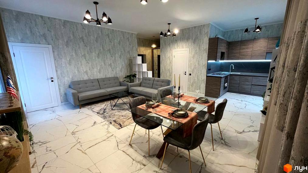 Інтер'єр квартири в ЖК Лелека з сірими диванами, скляним столом та кухнею з темними фасадами. Простора квартира з білою плиткою на підлозі та світлими стінами.