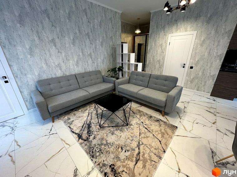 Інтер'єр квартири в ЖК Лелека з сірим диваном, журнальним столиком та килимом. Світла підлога з мармуровим візерунком.