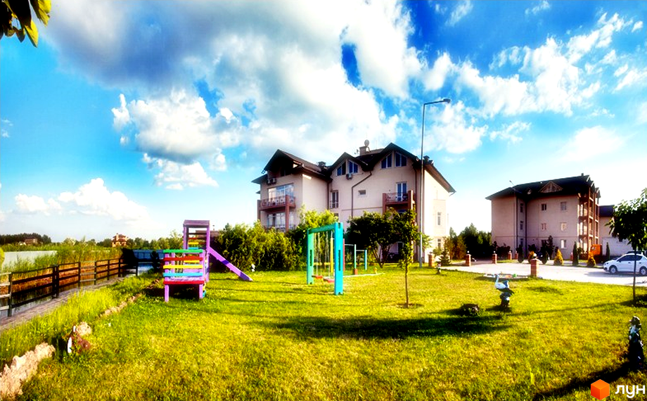 Житловий комплекс Бірюза з багатоповерховими будинками та дитячим майданчиком на доглянутій зеленій території біля водойми.