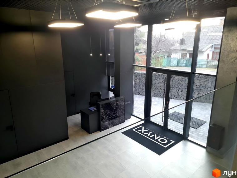 Вхідна група житлового комплексу ONYX sweet home з дверима та вікнами, що виходять на подвір'я з бруківкою та кам'яною огорожею.