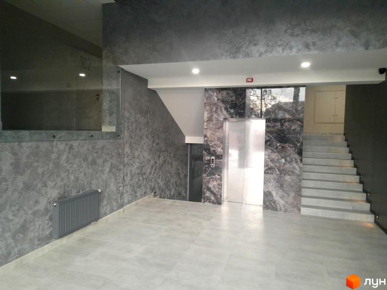 Сучасний інтер'єр холу житлового комплексу ONYX sweet home з ліфтом та сходами. Сірі стіни з декоративною штукатуркою та мармуровими вставками створюють елегантну атмосферу.