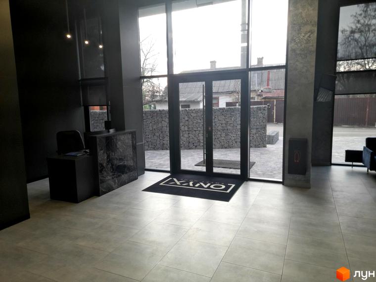 Вхідна група житлового комплексу ONYX sweet home з рецепцією та дверима на прибудинкову територію з кам'яною огорожею.