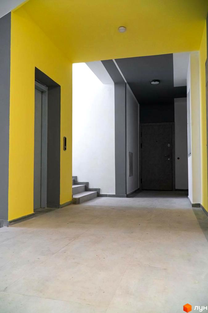 Інтер'єр поверху в Житловому районі Зелені Пагорби з ліфтом та сходами. Коридор з сіро-жовтим оздобленням та бетонною підлогою.