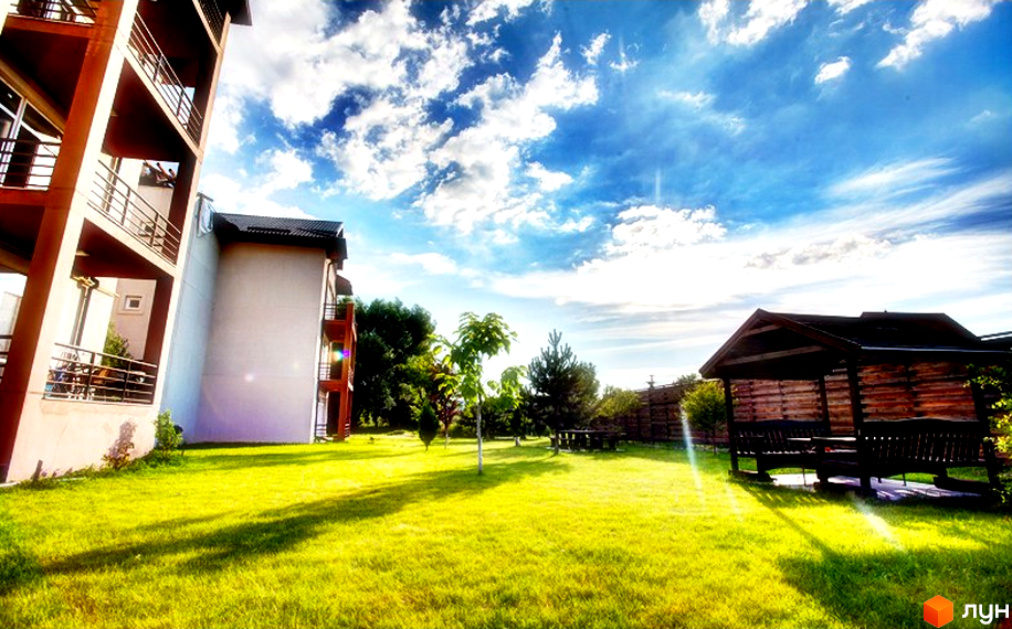 Житловий комплекс Бірюза. Зовнішній вигляд будівель з балконами та прибудинкова територія з альтанкою та газоном.