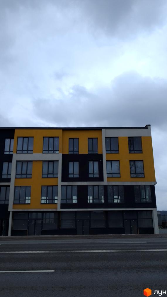 Фасад новобудови на Підволочиському шосе з жовтими та чорними елементами та великими вікнами. Будинок має геометричну форму та розташований біля дороги.
