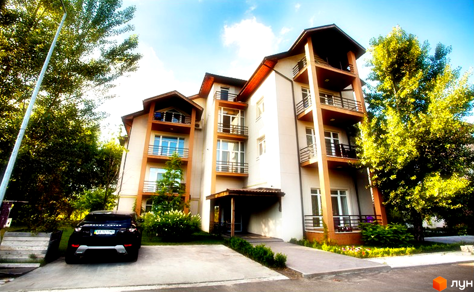 Житловий комплекс Бірюза. Багатоповерховий будинок з балконами та вікнами, прибудинкова територія з деревами та автомобілем.