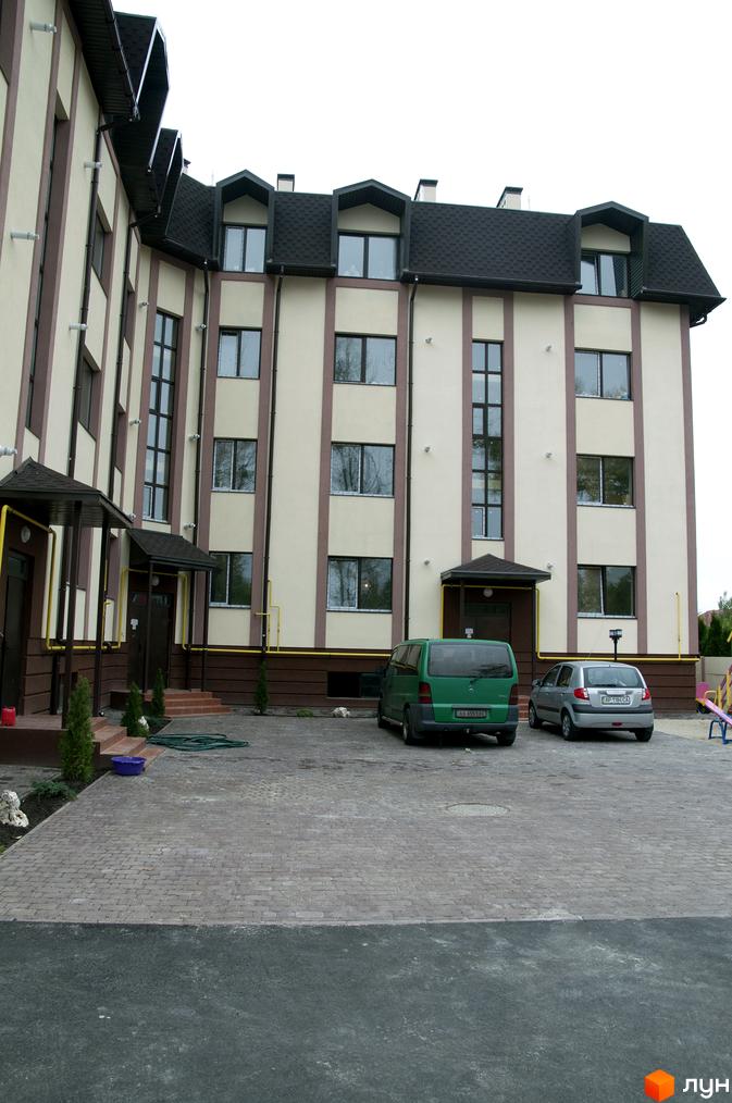 Житловий комплекс на вул. Червоноармійська, 14, з фасадом у світлих тонах та прибудинковою територією з паркувальними місцями.