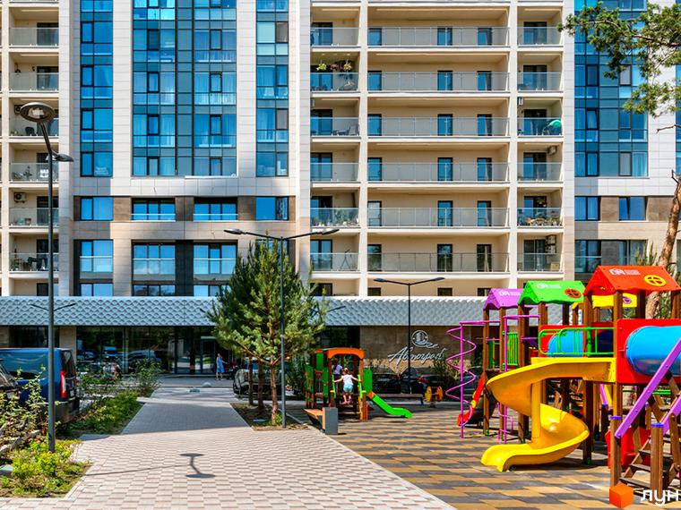 Новобудова ЖК Автограф з фасадом з панорамними вікнами та дитячим майданчиком біля будинку. Зовнішній вигляд комплексу та прибудинкова територія.