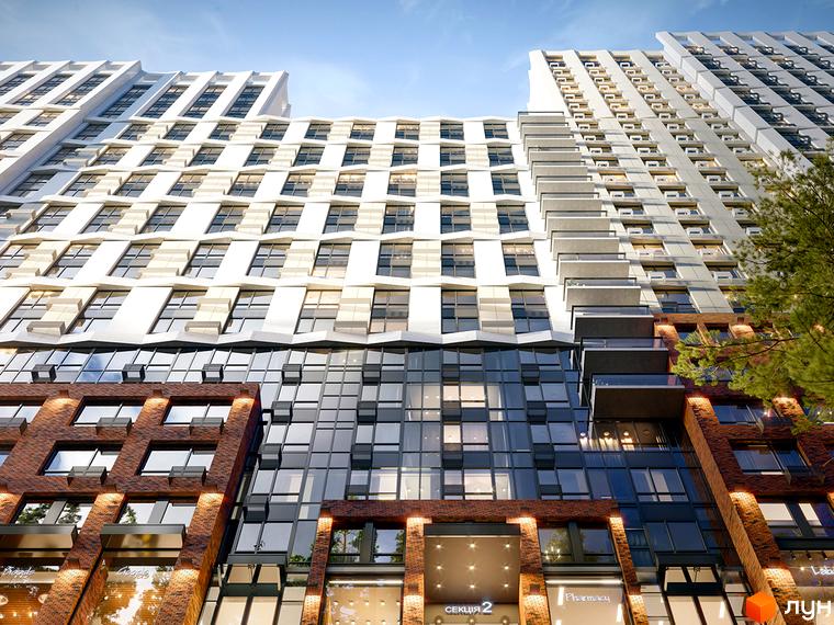 Зовнішній вигляд новобудови ЖК Новий Автограф із цегляним та скляним фасадом, балконами та великою кількістю вікон. Будівельний проєкт розташований під блакитним небом.