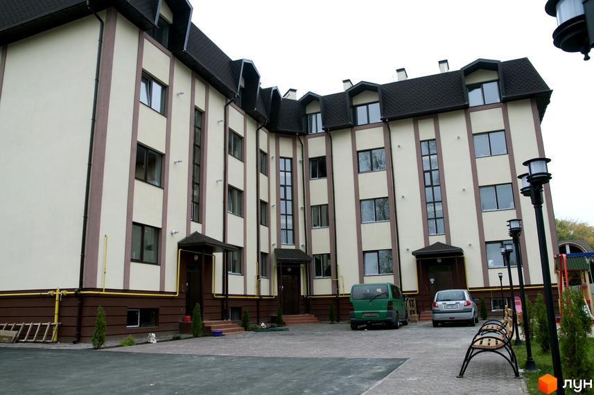 Житловий комплекс на вул. Червоноармійська, 14. Вид на фасад будинку та прибудинкову територію з парковкою та ліхтарями.