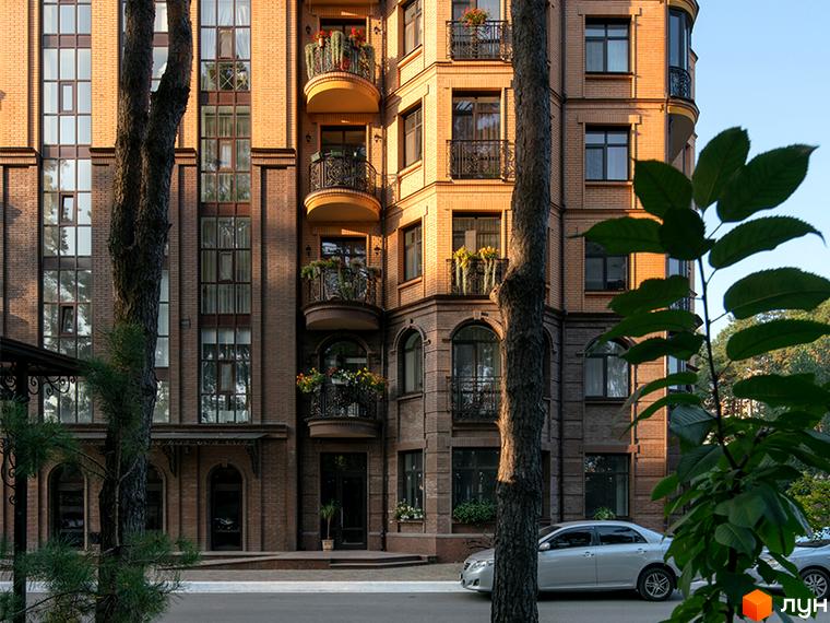 Зовнішній вигляд Житлового комплексу Соборний: багатоповерховий цегляний будинок з балконами та деревами на прибудинковій території.
