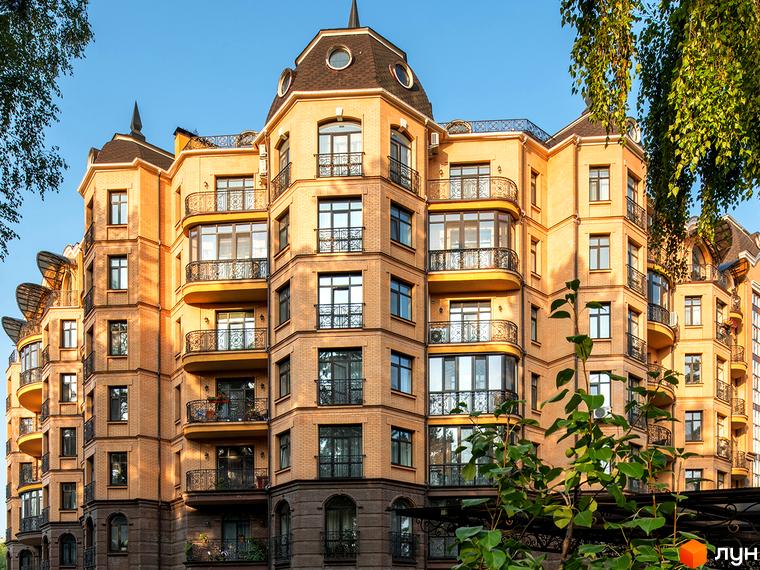 Сучасний житловий комплекс Соборний з балконами та декоративними елементами. Прибудинкова територія озеленена деревами та кущами.