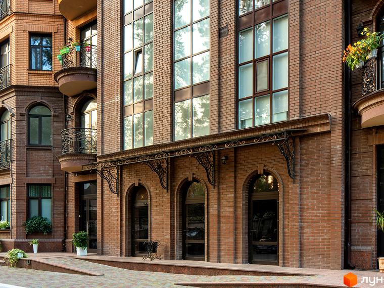 Житловий комплекс Соборний з цегляним фасадом та балконами. Прибудинкова територія з зеленими насадженнями та плиткою.