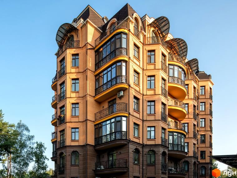 Житловий комплекс Соборний з фасадом з червоної цегли та балконами. Прибудинкова територія з зеленими насадженнями та парковкою.