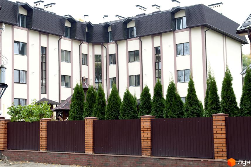 Зовнішній вигляд фасаду новобудови на вул. Червоноармійська, 14 з акуратним парканом та зеленими насадженнями. Опис житлового комплексу.