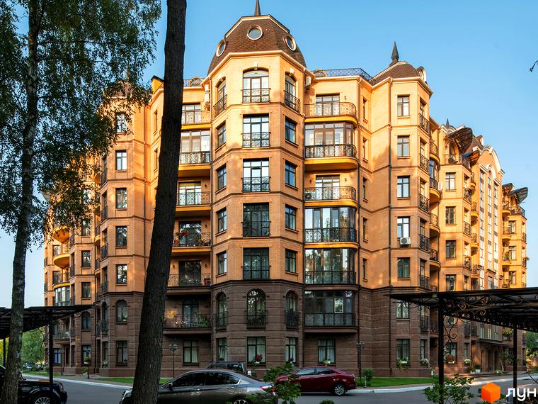 Житловий комплекс Соборний з фасадом з червоної цегли та великими вікнами. Прибудинкова територія озеленена деревами та газонами.