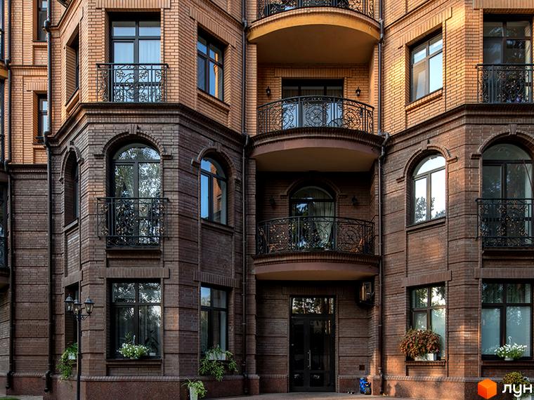 Фасад житлового комплексу ЖК Соборний з великими вікнами та балконами. Прибудинкова територія озеленена рослинами та освітленням.