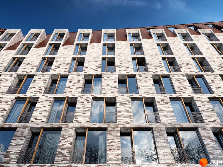 Фасад житлового комплексу LUCKY LAND з багатокольорової цегли та великими вікнами. На верхніх поверхах дахові вікна та металевий дах.