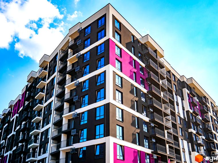 Зовнішній вигляд багатоповерхового будинку в Житловому районі Family Plaza. На фото видно фасад будинку з вікнами та балконами.