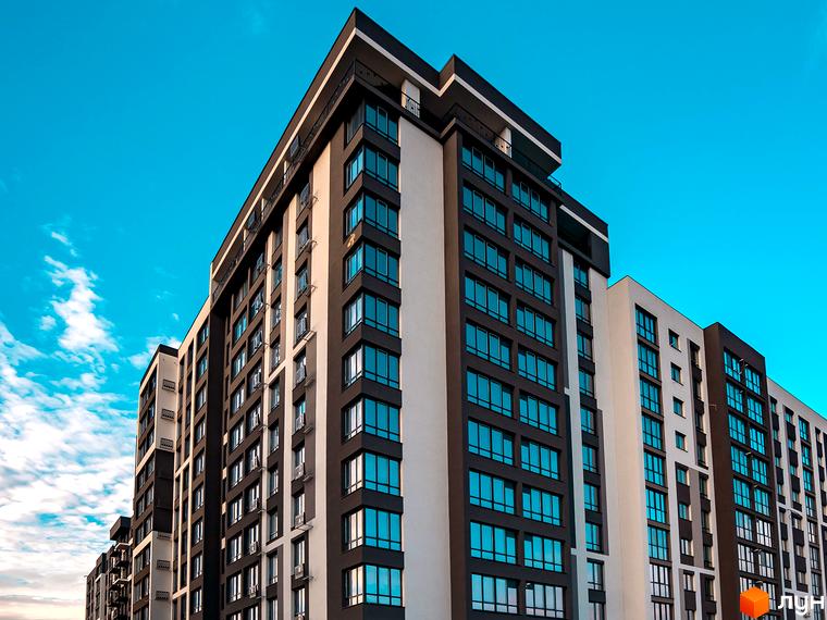 Зображення багатоповерхового будинку Житлового комплексу Паркова Алея з великими вікнами. Навколо новобудови блакитне небо.