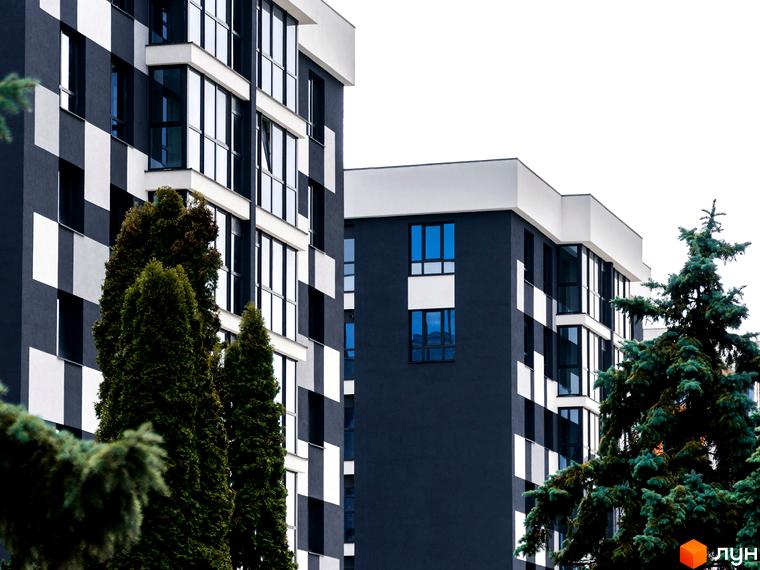 Житловий комплекс Union з фасадами в чорно-білу клітинку та великими вікнами. Поруч високі хвойні дерева.