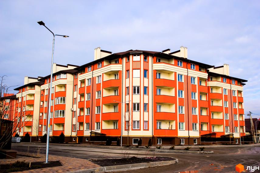 Житловий комплекс Щасливий: фасади будівель з балконами та вікнами, прибудинкова територія з дорогою та тротуаром.