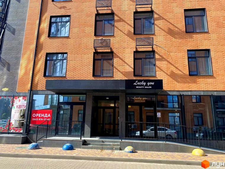 Фасад житлового комплексу Plaza Kvartal з цегляним оздобленням та великими вікнами. Перед будинком розташовані сходи та тротуар з декоративними елементами.