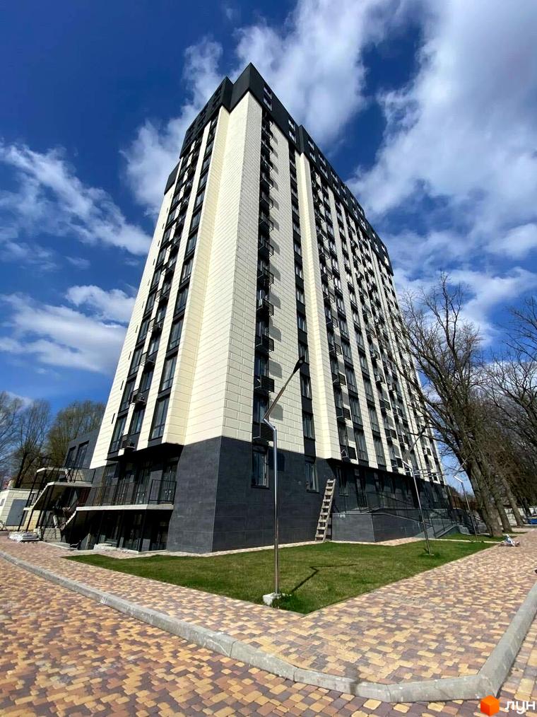 Багатоповерховий будинок Житлового комплексу Park Plaza з чорно-білим фасадом та прибудинковою територією з газоном і бруківкою.