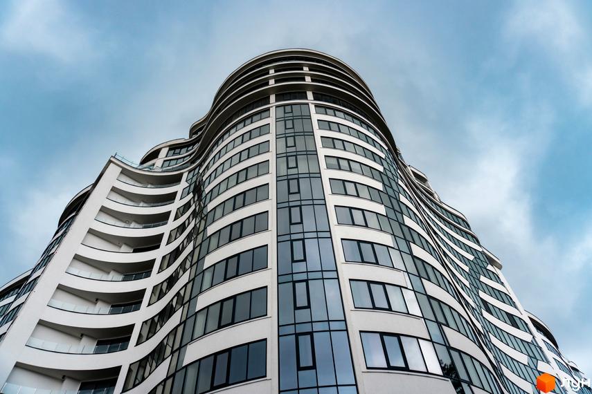 Зображення фасаду багатоповерхового будинку Житлового комплексу Parus. Вигляд будівлі з великою кількістю вікон на фоні хмарного неба.