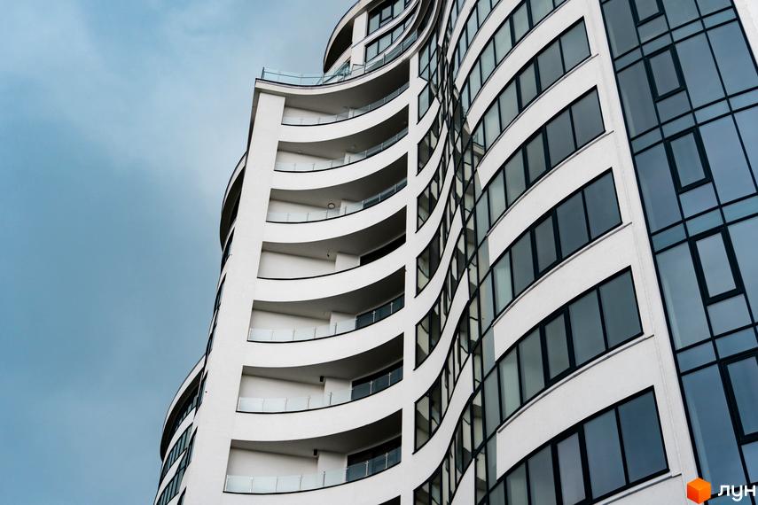 Зображення фасаду Житлового комплексу Parus з великими вікнами та балконами. Вигляд новобудови на фоні неба.