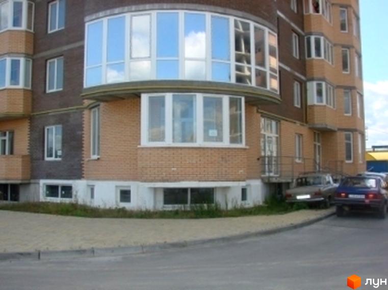 Житловий комплекс на вул. Гончара, 3 з великими вікнами та прибудинковою територією, що включає парковку.