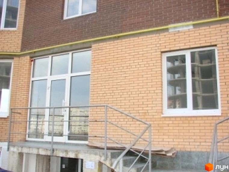 Фасад житлового комплексу вул. Гончара, 3 з великими вікнами та виходом на сходи. Прибудинкова територія з підходами та озелененням.