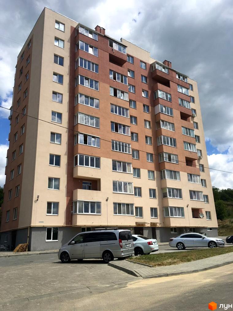 Багатоповерховий житловий комплекс на вулиці Джона Ленона, 1, 3, з автомобілями на фоні.