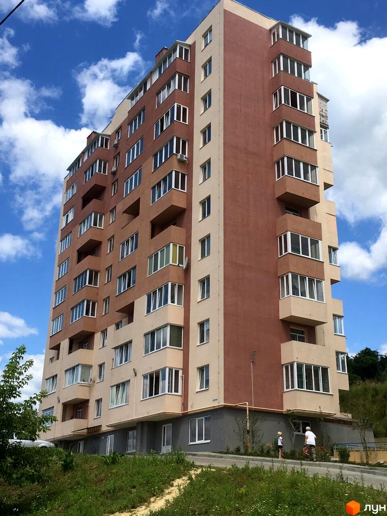 Багатоповерховий житловий комплекс на вулиці Джона Леннона, 1, 3, з цегляним фасадом та балконами. Навколо будинку зелена зона та дорога.