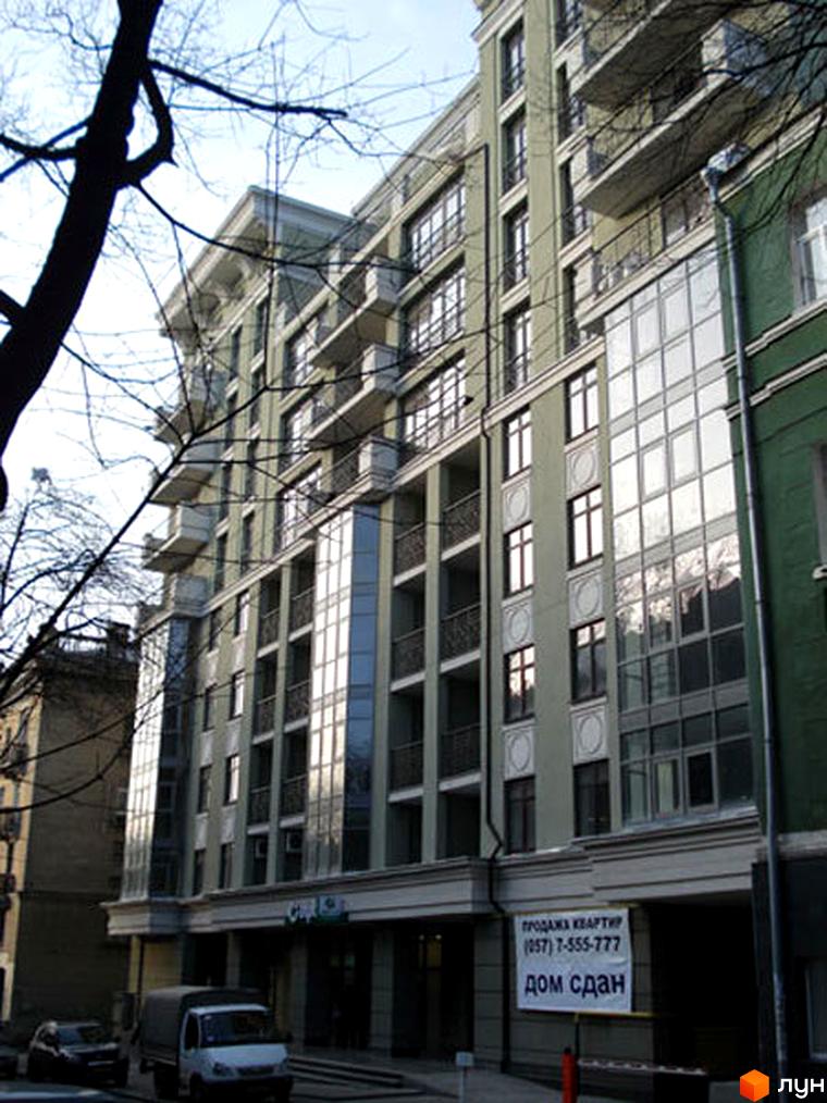 Житловий комплекс на вул. Чернишевська, 7, з фасадом у світлих тонах та балконами. Прибудинкова територія з паркувальними місцями.