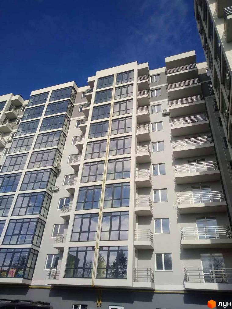Висотна будівля ЖК Фортеця з панорамними вікнами та балконами. Навколо будинку видно блакитне небо.