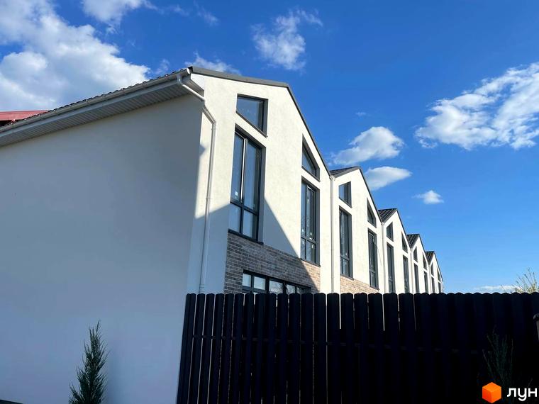 Зовнішній вигляд таунхаусів West Homes з білою штукатуркою та темним парканом на тлі блакитного неба з хмарами. Опис новобудови для просування сайту.