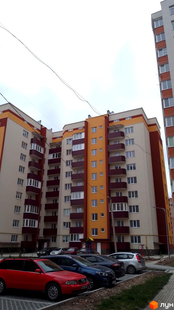 Фасад новобудови на вулиці Смакули, 2, з балконами та вікнами, прибудинкова територія з автомобілями.