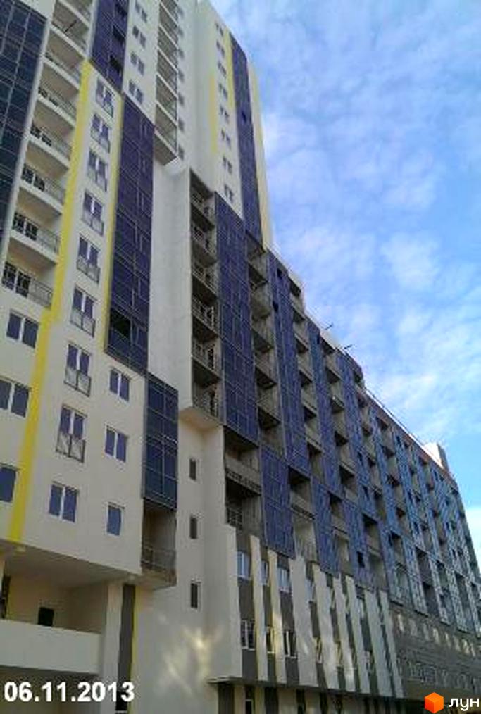 Зовнішній вигляд новобудови ЖК Аксіома: висотна будівля з балконами та сонячними панелями на фасаді. Небо з хмарами.