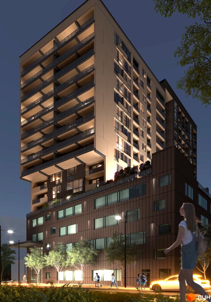 Житловий комплекс AUROOM AIR з цегляним фасадом та балконами, освітлений ввечері. Поруч розташовані дерева та тротуар з людьми.